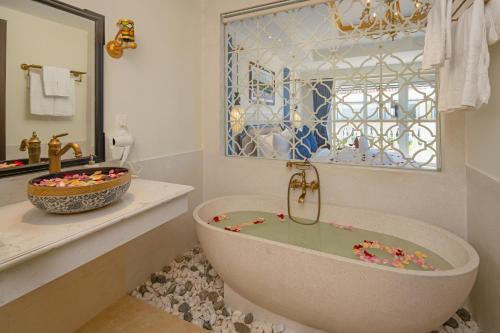 会安Hoi An Blue Sky Boutique Hotel & Spa的带浴缸、水槽和镜子的浴室