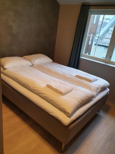 卑尔根Nygårdsgaten apartments的一张带白色床单和枕头的床,靠窗