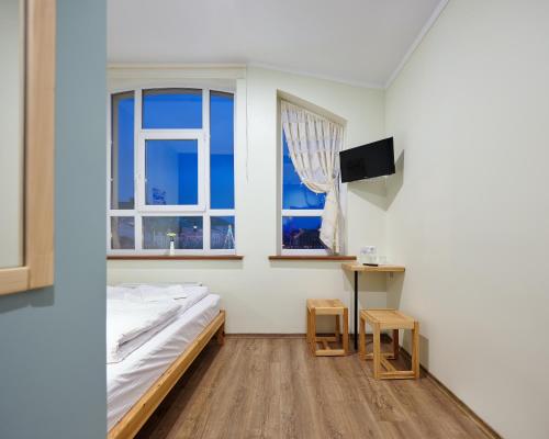 赫梅利尼茨基DREAM Hostel Khmelnytskyi的一间卧室配有一张床、一张桌子和两个窗户