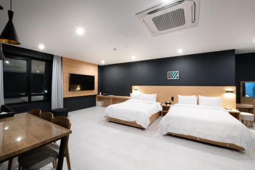 釜山Mipo Oceanside Hotel的一间酒店客房,设有两张床和一间餐厅