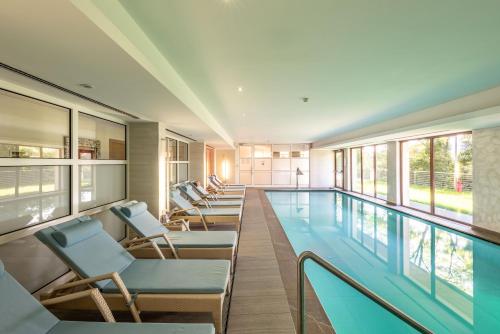 特伦托玛杜左别墅酒店的一个带椅子的大型游泳池和一个游泳池