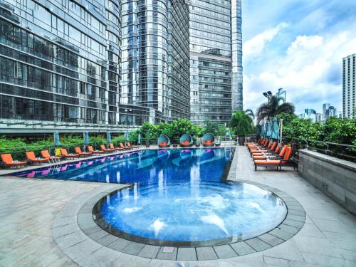 广州广州辉盛阁国际公寓(城央户外度假泳池)的一座带椅子和建筑的大型游泳池