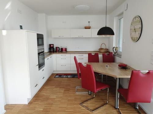 大雷申Ferienwohnung Seenland的厨房配有木桌和红色椅子