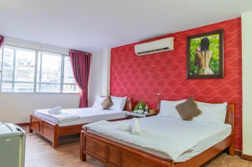 胡志明市Aqua Long Son Hotel的一间卧室设有两张床和红色的墙壁