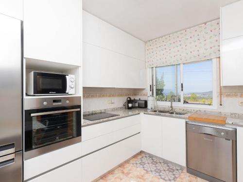 卡拉费尔Holiday Home Oasis by Interhome的厨房配有白色橱柜、微波炉和窗户。