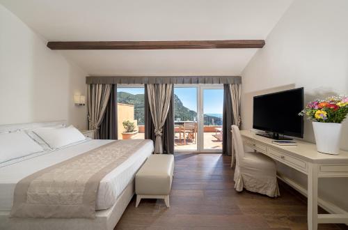 圣托斯特凡诺港Boutique Hotel Torre Di Cala Piccola的一间卧室配有一张床和一张书桌及电视