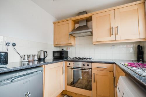 赫尔Hullidays - Victoria Dock Residence的厨房配有木制橱柜和炉灶烤箱。