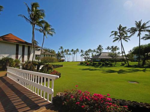 科洛阿Castle Kiahuna Plantation & Beach Bungalows的一座带白色围栏的房子和一座棕榈树庭院