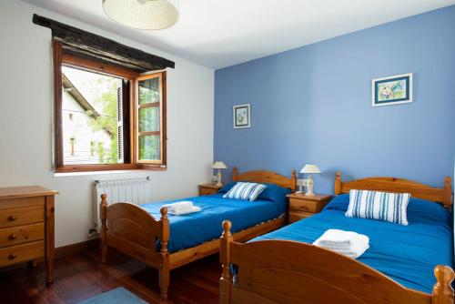 艾斯柯尔兹乡村阿丽诺乡村别墅的卧室设有两张床铺和蓝色的墙壁