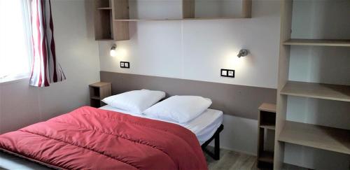 Pléboulle露营弗莱士金刚假日公园的一间卧室配有一张带红色床单和枕头的床。