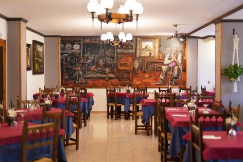 埃斯卡洛纳钦克酒店的餐厅设有桌椅,墙上挂有绘画作品