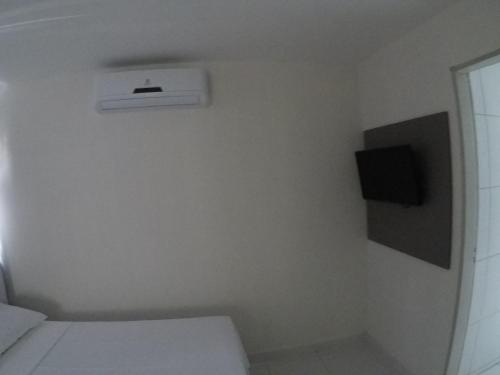 若昂佩索阿Pousada Tambaú的一间白色的小房间,配有床和电视