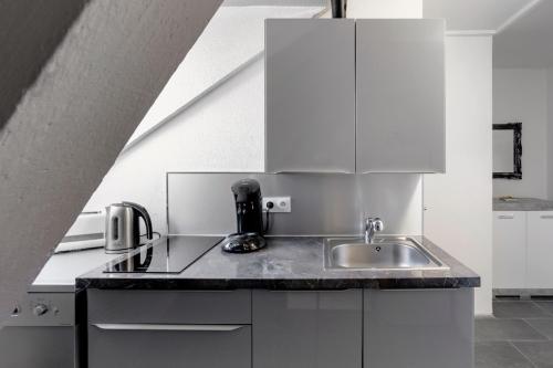 圣路易Comfort Stay Basel Airport 3B46的厨房配有白色橱柜和水槽