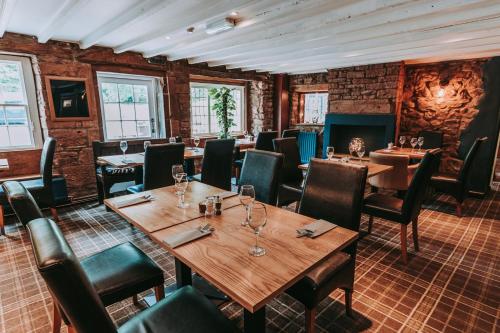 阿普比阿普比皇家橡树酒店的餐厅设有木桌、椅子和砖墙