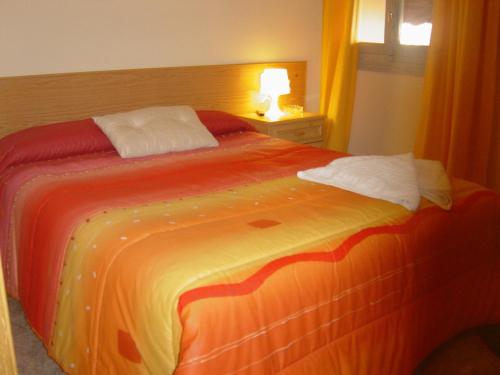 马德里埃米利奥巴拉哈斯旅馆的一间卧室配有一张带橙色和黄色毯子的床