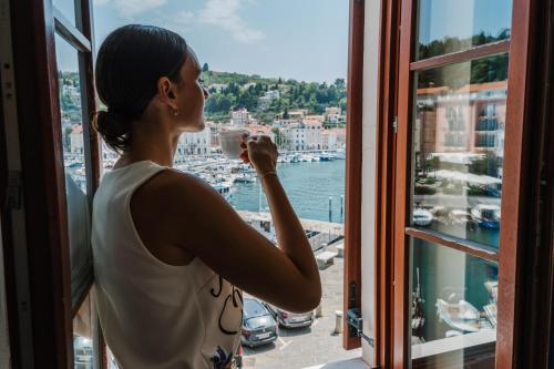 皮兰Vila Piranesi Apartments - Parking included的把港口的照片从窗口拿出来的妇女