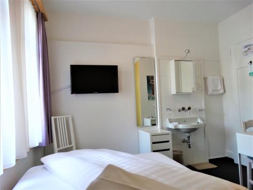 达沃斯邦德奈霍夫酒店的卧室配有一张床和一个水槽,墙上配有电视。