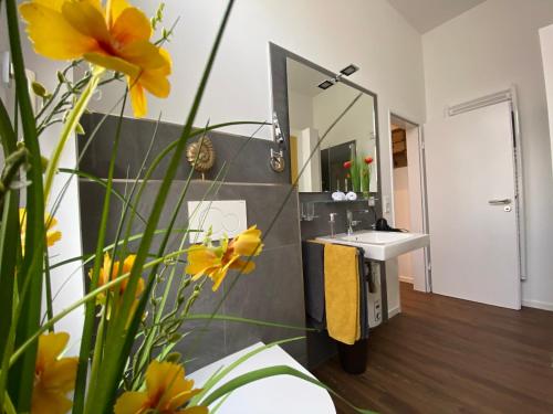 奥尔登堡Quartier 1903的浴室设有水槽、镜子和黄色的鲜花
