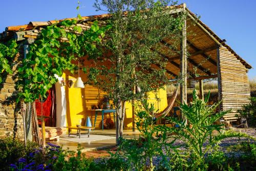 奥德米拉The Hobbit House - Montes da Ronha的花园内带凉棚的黄色房子