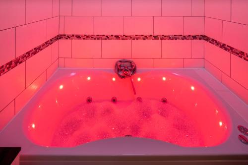 米尔顿凯恩斯The Railway Inn - 3 Bed Luxury Stay的粉红色瓷砖浴室内的红色浴缸