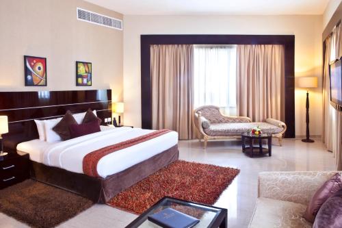 迪拜里卡地标酒店的酒店客房设有一张大床和一张沙发。