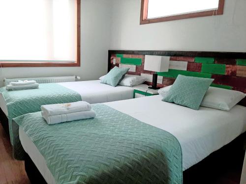 蓬塔阿雷纳斯Hostal Buenavista Patagonia的一间设有三张床的客房,配有绿色和白色的床单
