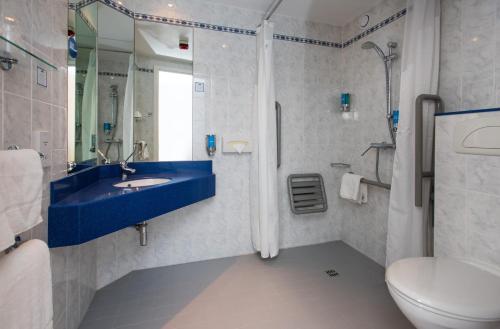 汤顿Holiday Inn Express Taunton East, an IHG Hotel的浴室配有蓝色水槽和卫生间。