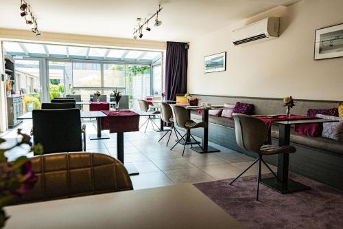 登德尔蒙德Abalona Hotel & Apartments的餐厅设有桌椅和大窗户。