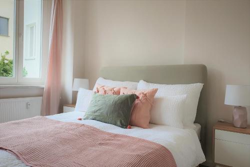 森夫滕贝格PB Ferienwohnungen - FeWo 2 - Stilvoll eingerichtetes Apartment im Herzen Senftenbergs的一张带粉色和绿色枕头的床