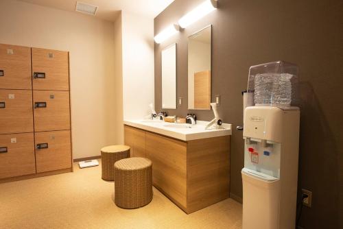 东京Wires Hotel Shinagawa Seaside的一间带水槽和镜子的浴室以及一台冰箱