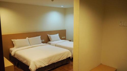 马六甲906 Hotel Melaka Raya的客房配有2张带白色枕头的床。