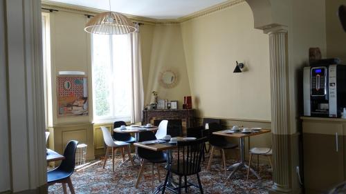 迪纳尔Cit'Hotel Les Alizes的一间带桌椅的用餐室和窗户。