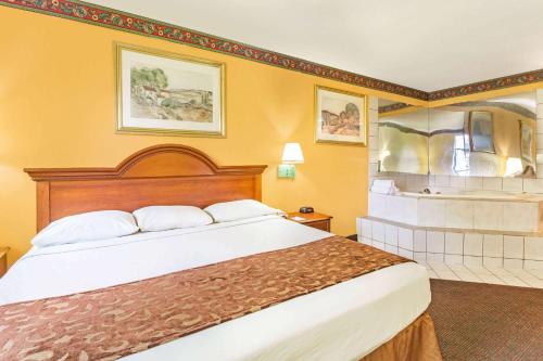 湖城Howard Johnson by Wyndham Lake City的酒店客房设有一张大床和一个浴缸。