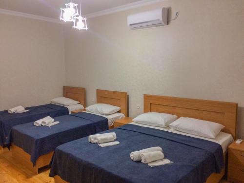 西格纳吉Guest House Maradona的客房内的三张床,配有蓝色的床单和毛巾