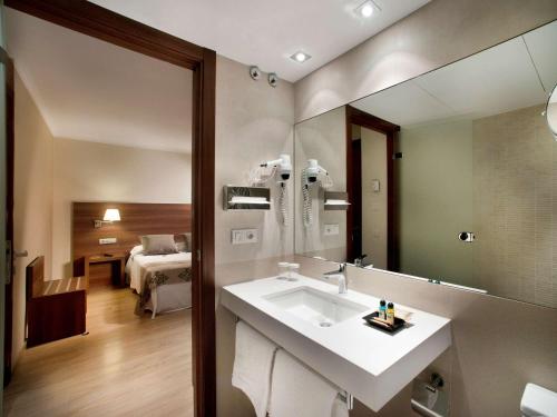 菲格拉斯Ibis Styles Figueres Ronda的一间带水槽和镜子的浴室以及一间卧室