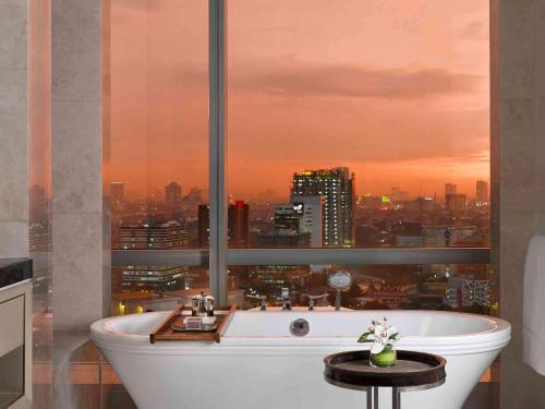 雅加达雅加达莱佛士酒店的带浴缸的浴室,享有城市景观