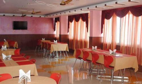 乔斯希马特Hotel Shail Shikhar的一间配备有桌椅和红色窗帘的用餐室