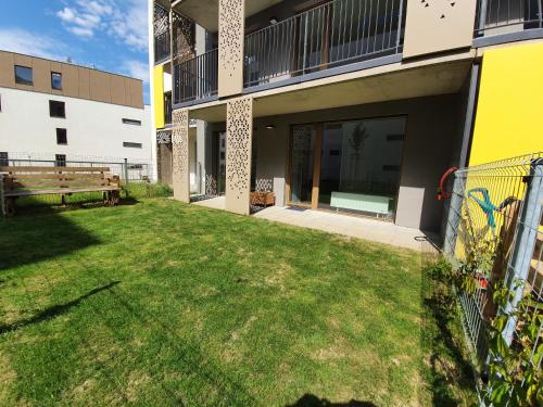 比尔森MODERN APARTMENT WITH TERRACE AND GARAGE in THE CITY CENTER的一座带草地庭院的建筑的后院