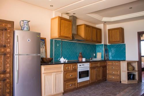 依索安Imsouane Surf Paradise的厨房配有木制橱柜和冰箱。