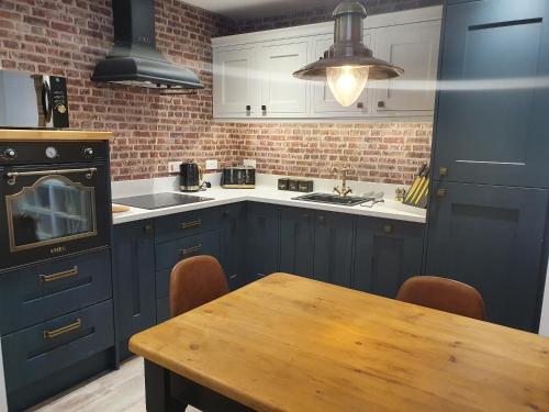 布恩The Snug Bourne的厨房配有蓝色橱柜和木桌