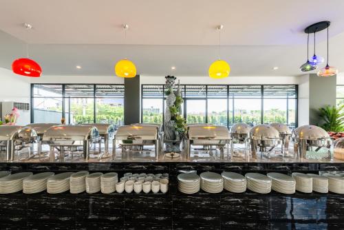 Bang HiaAurora Suvarnabhumi的一间设有白色板块和桌子的餐厅以及窗户