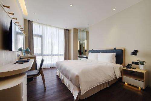 台北杰仕堡有氧酒店的酒店客房设有一张大床、一张书桌和一张书桌。