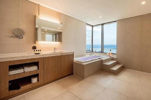 江陵市SL Hotel Gangneung的一间带水槽和浴缸的浴室以及窗户。