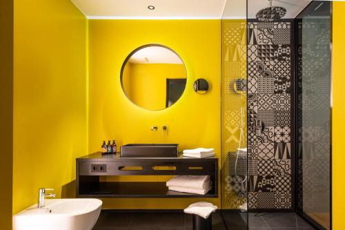 梅拉诺Prinz Rudolf Smart Hotel的黄色的浴室设有水槽和镜子