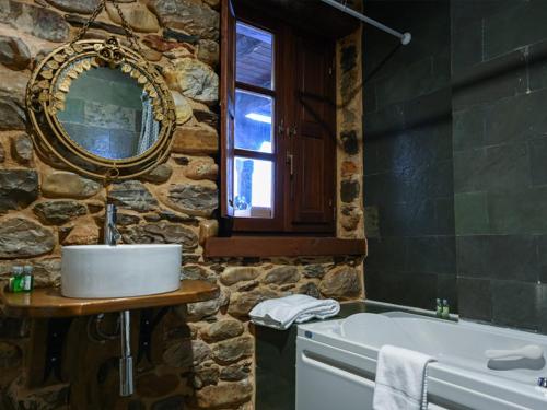 VilladepalosRestaurante - Hotel La Tronera的石质浴室设有水槽和浴缸。