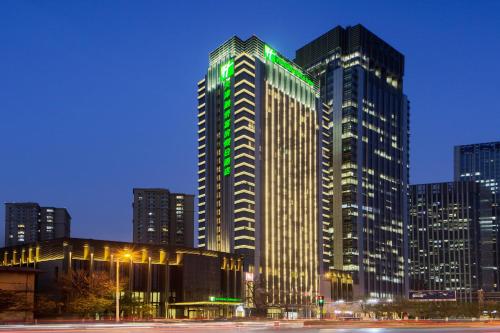 天津天津融侨套房假日酒店的一座高大的建筑,上面有绿灯