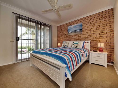 尼尔森湾Bushmans, 9 24 Tomaree Street - Spacious townhouse with air conditioning and close to Nelson Bay Town Centre的一间卧室设有一张床和砖墙