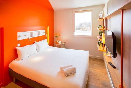 博韦ibis budget Beauvais Aeroport的一间卧室配有一张白色的床和橙色的墙壁