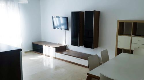 休达Beatiful and full-equipped flat in the city center的客厅配有桌子和墙上的电视