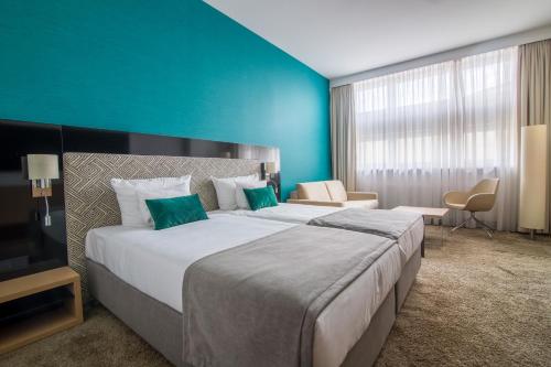 卡托维兹波赞托沃运动酒店的一间卧室设有一张大床和蓝色的墙壁